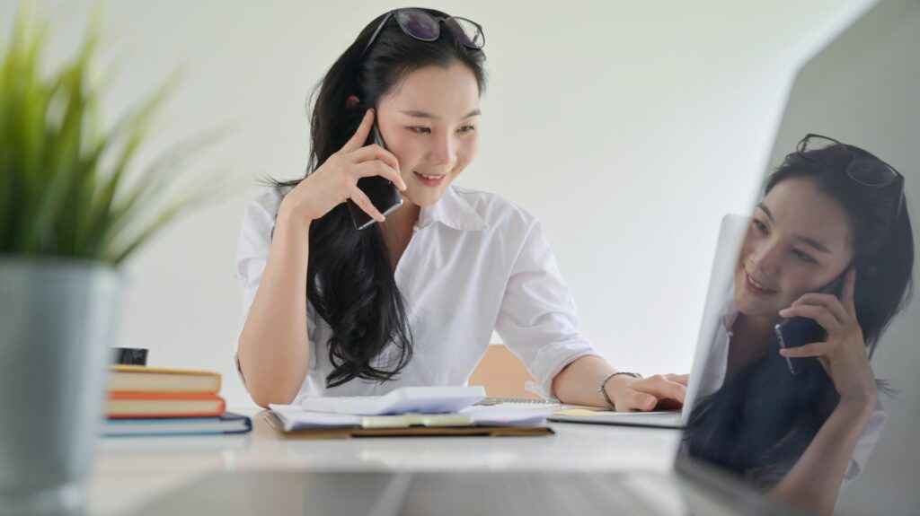 A smiling young woman using a smartphone to make business contacts